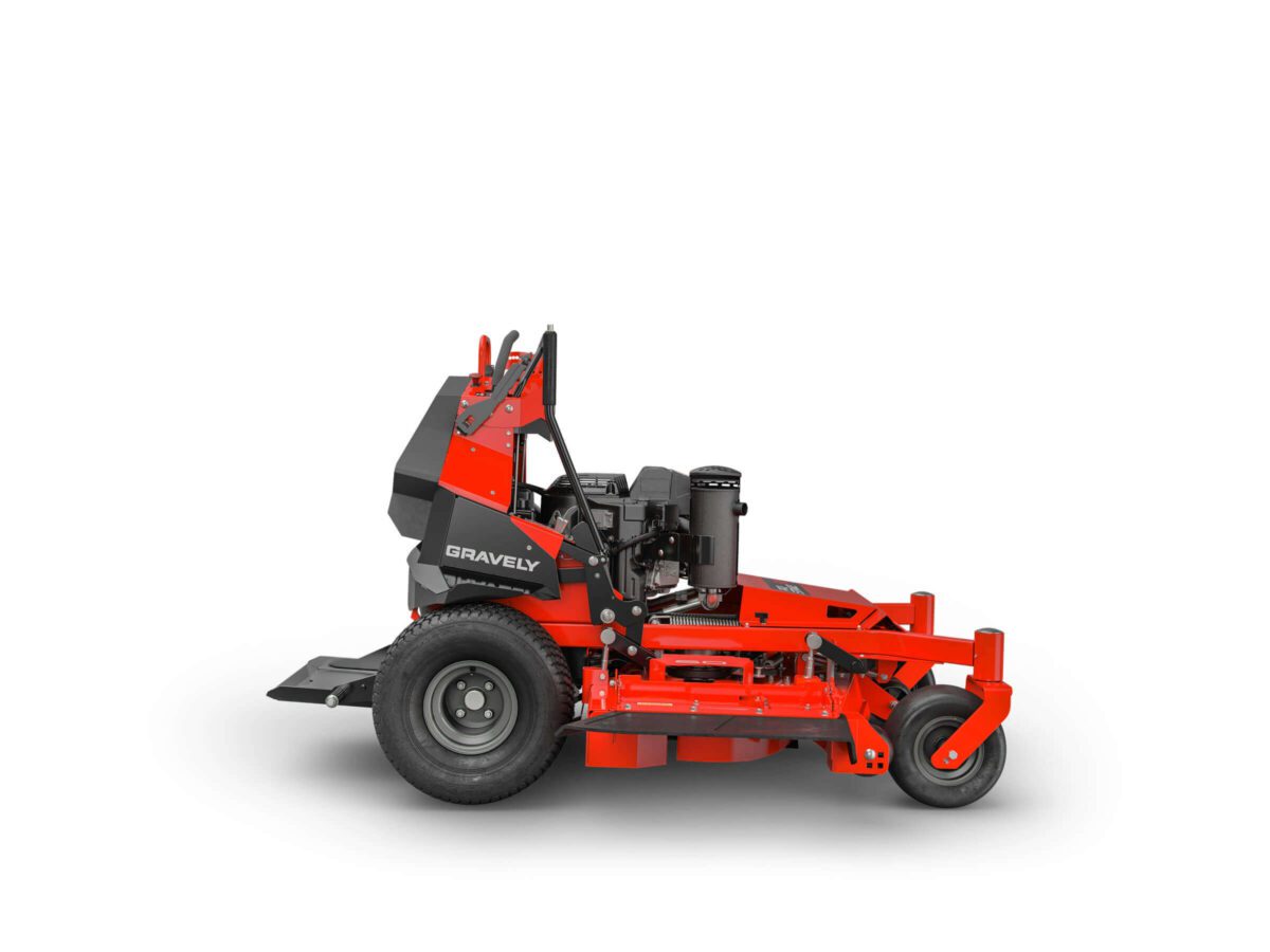 Red and black Gravely stand-on lawn mower with large rear tires, small front wheels, and visible engine, viewed from the side on a white background.