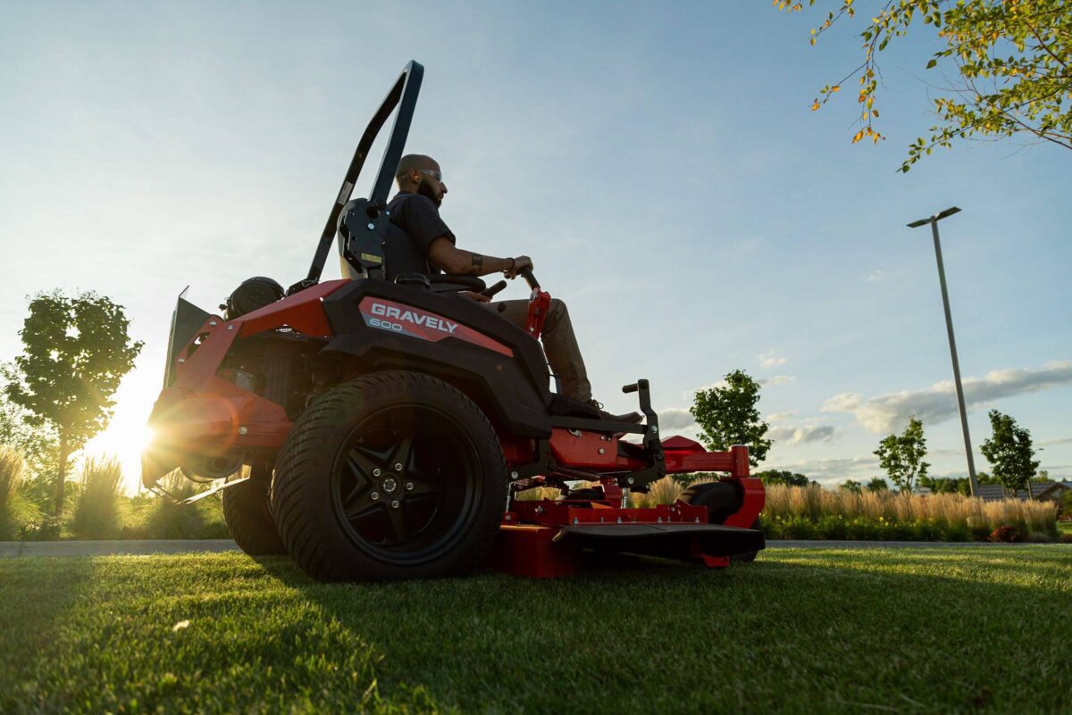 A person mowing a lawn on a red riding mower branded 