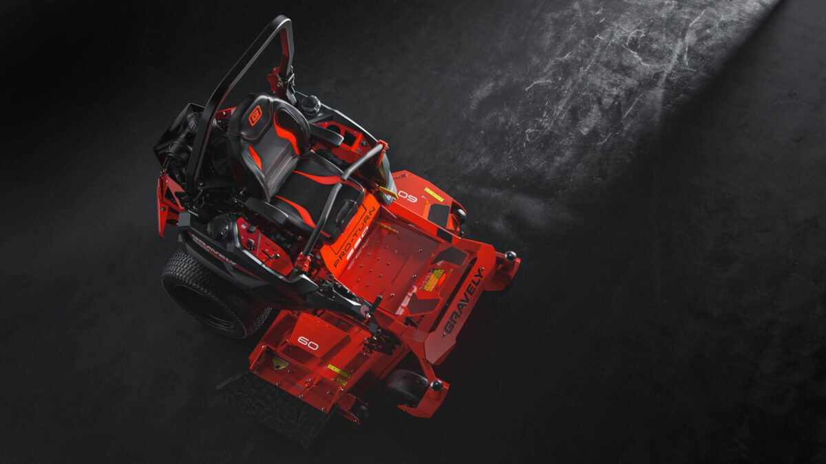 Red and black riding lawn mower against a dark background, with visible seat, controls, and grass catcher.
