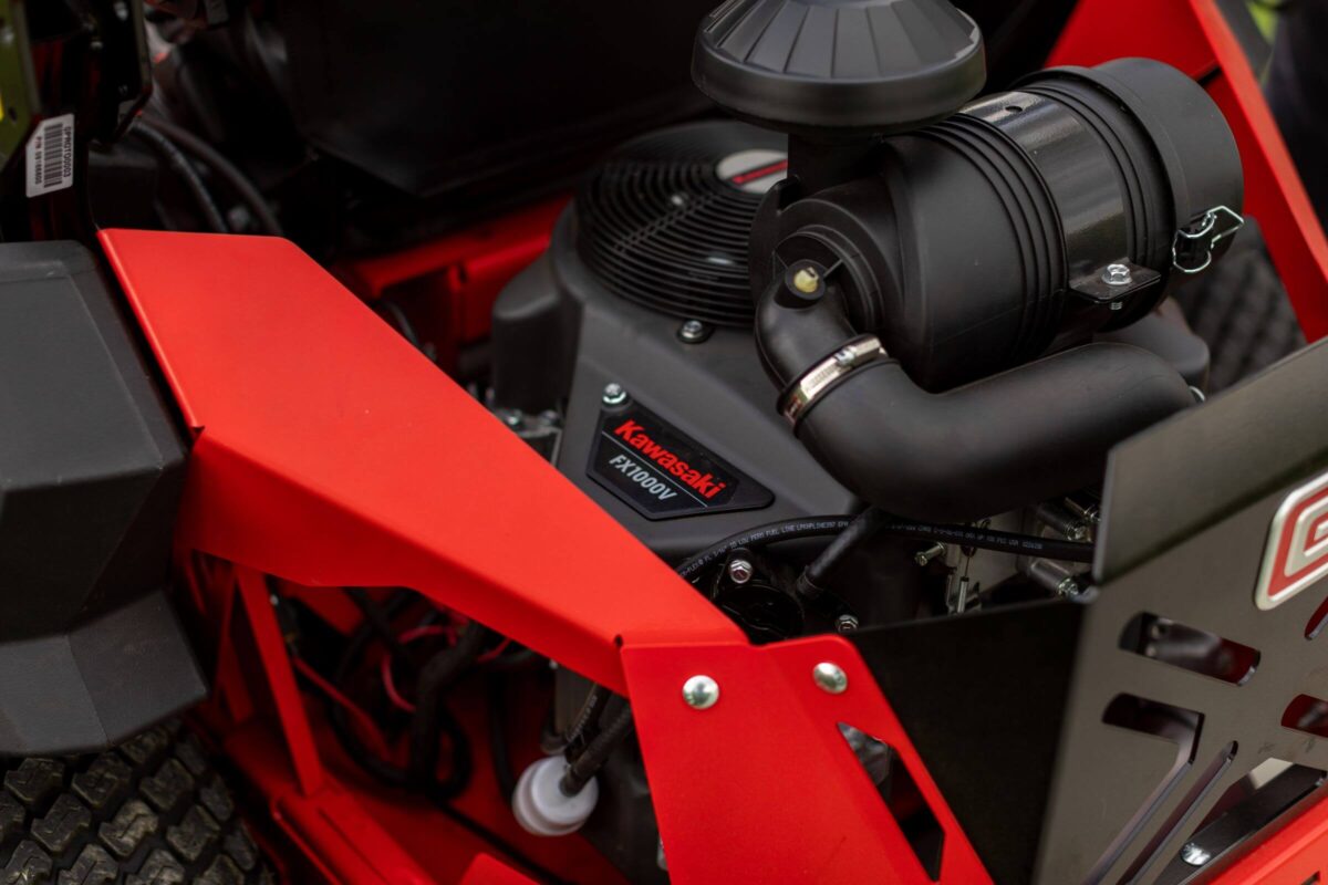Close-up of a Kawasaki engine inside a red metal frame, showcasing the brand logo and mechanical components.