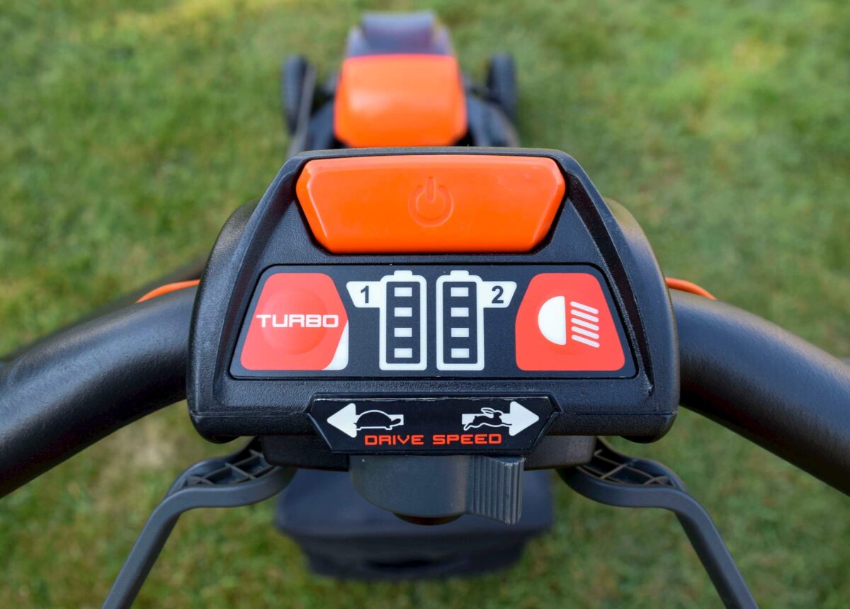 Close-up of an orange and black lawn mower control panel showing buttons for turbo mode, drive speed options, and power.
