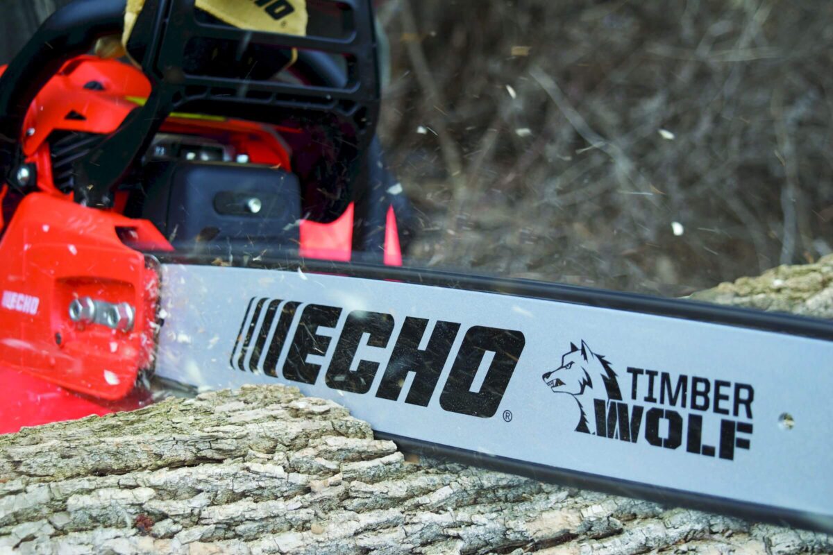 Chainsaw cutting through a tree trunk. The saw is branded with 