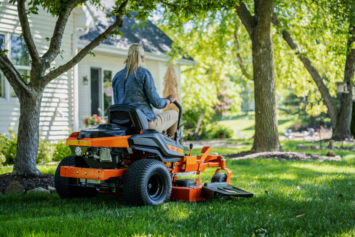 woman mowing lawn on a lawn mower